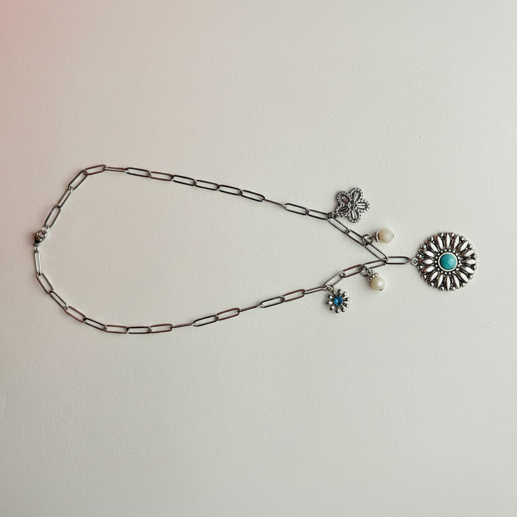 Silver necklace with decorative pendants on a light gray background