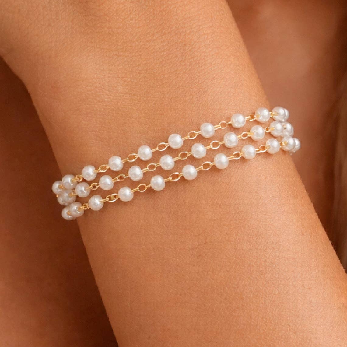 dainty Pearl bracelet on a person's wrist with a neutral background
