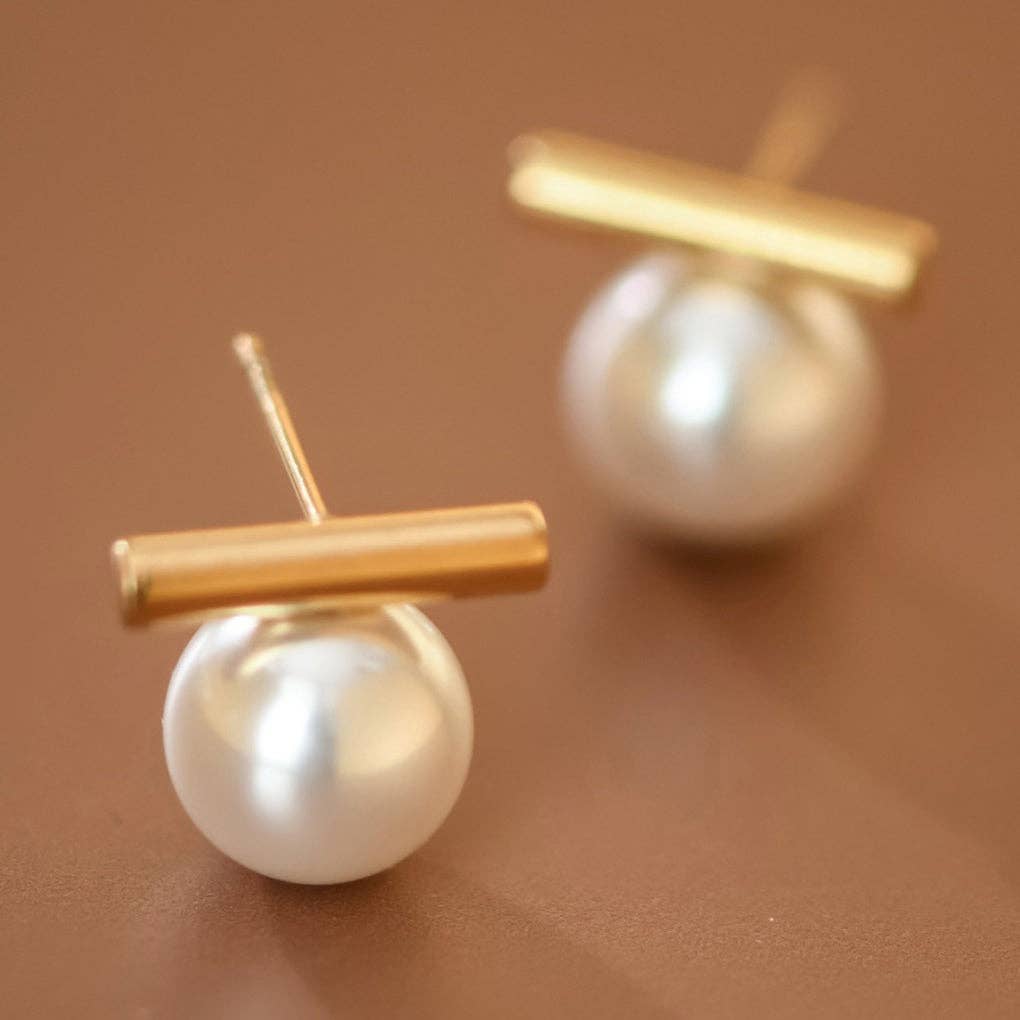 Pearl earrings with gold bars on a brown background