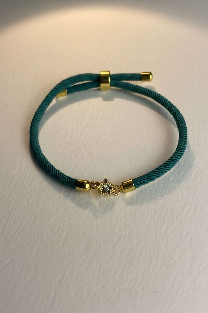 Green bracelet with gold clasp on a light gray background