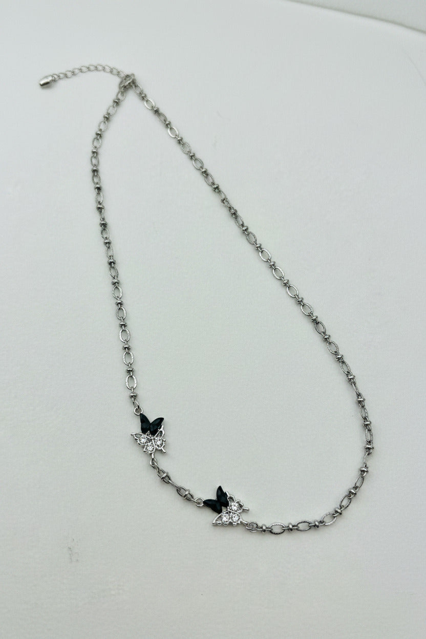 Silver chain necklace with butterfly-shaped charms on a white background