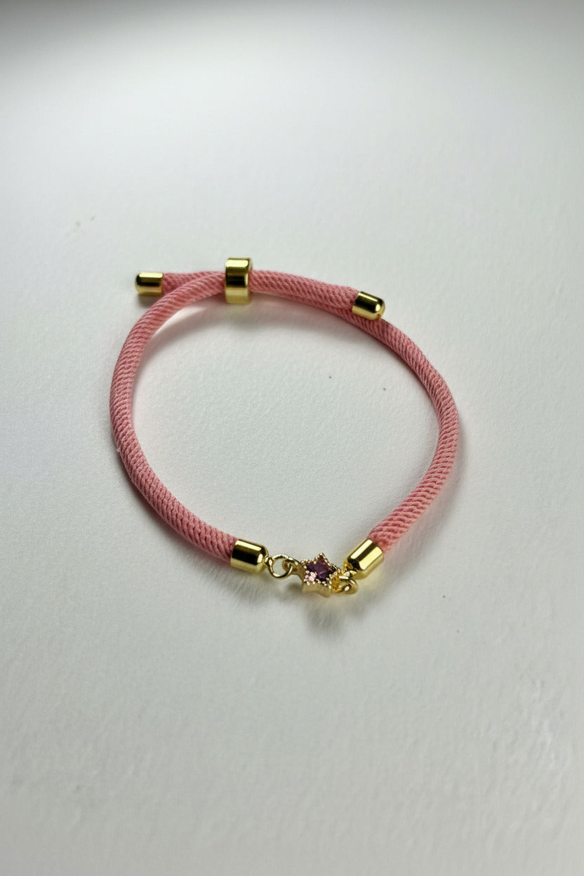 Pink bracelet with gold accents on a light gray background