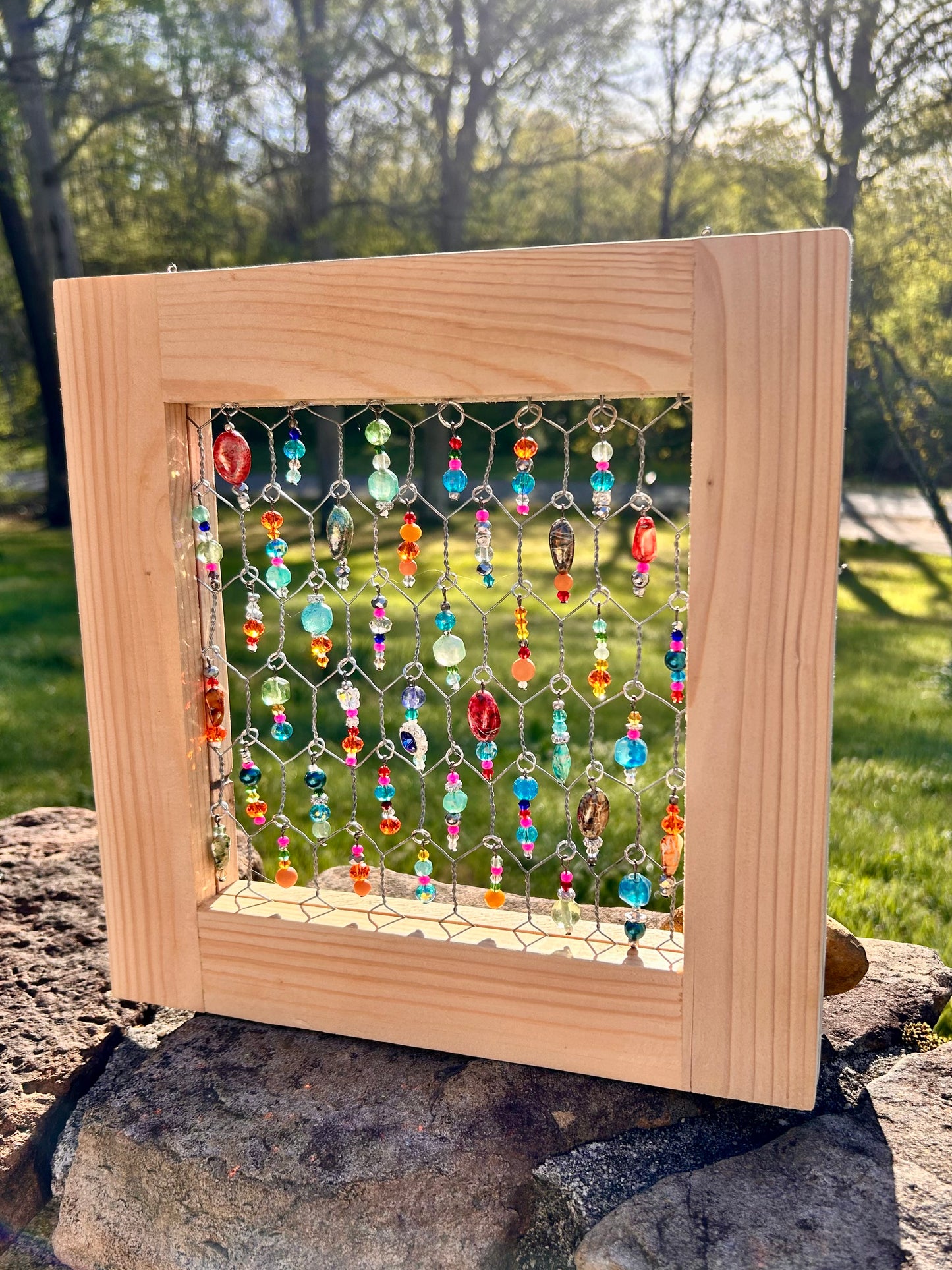 Wooden frame with colorful beaded artwork on a natural background
