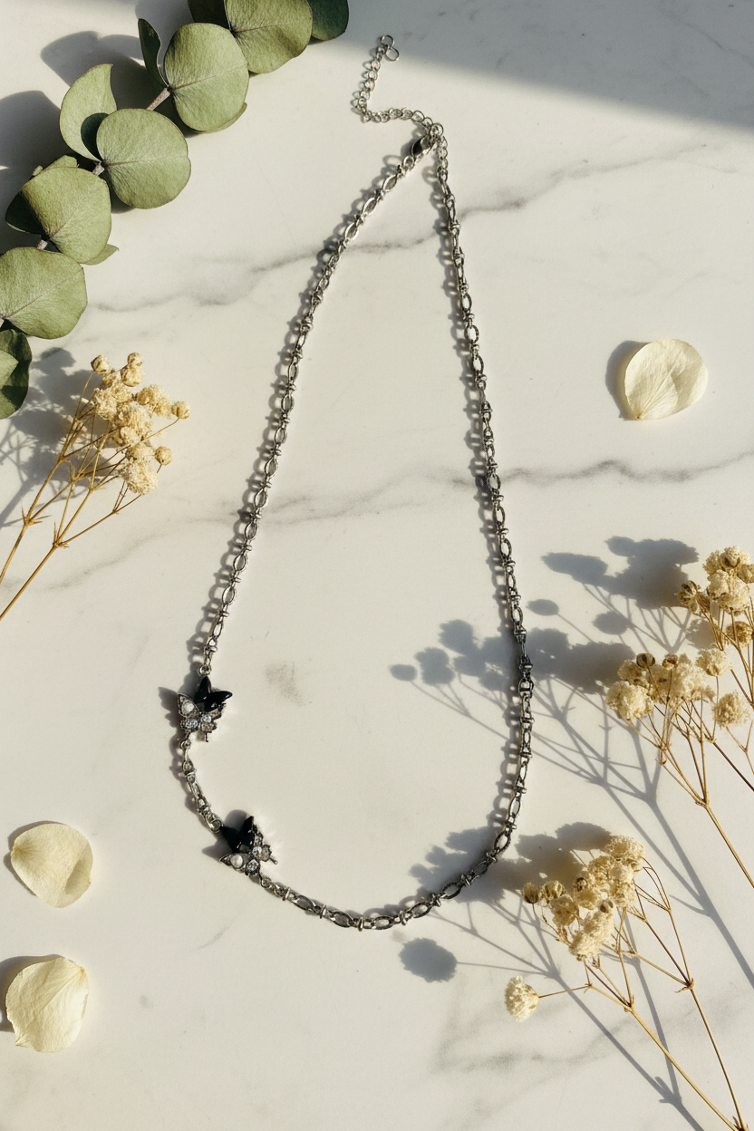 Silver necklace with star and butterfly pendants on a light gray background
