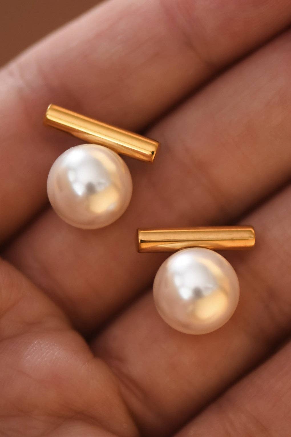 Pearl earrings with gold posts on a hand
